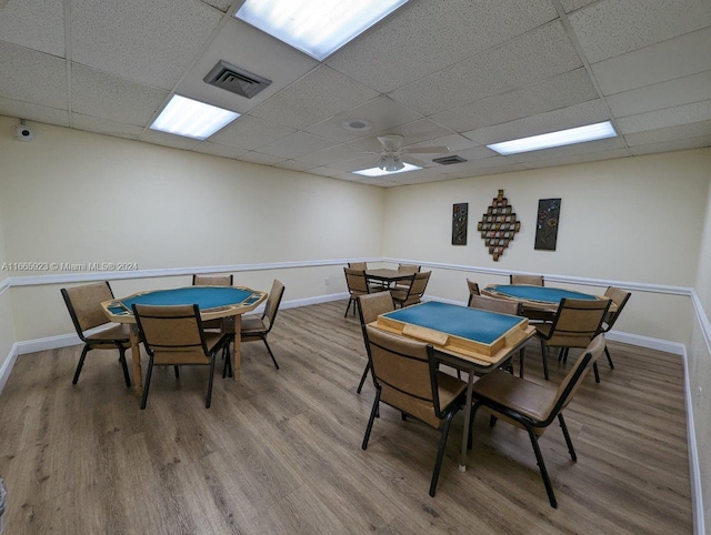 dining room with ceiling fan, hardwood / wood-style flooring, and a drop ceiling