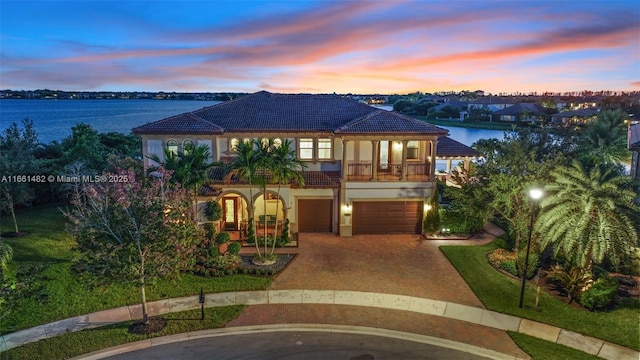 view of front of property with a balcony, a garage, and a water view