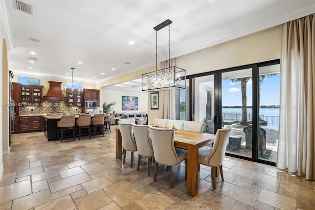 dining area featuring a healthy amount of sunlight, a water view, french doors, and ornamental molding