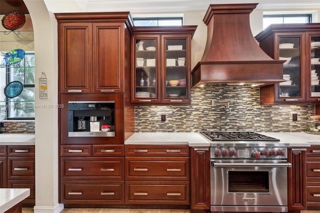 kitchen with decorative backsplash, luxury range, and custom range hood