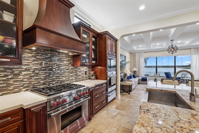 kitchen with decorative light fixtures, beamed ceiling, sink, custom exhaust hood, and stainless steel appliances