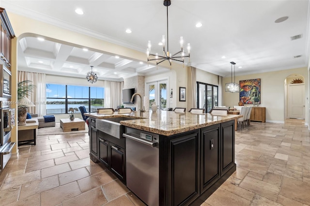 kitchen featuring pendant lighting, sink, stainless steel appliances, a notable chandelier, and a center island with sink