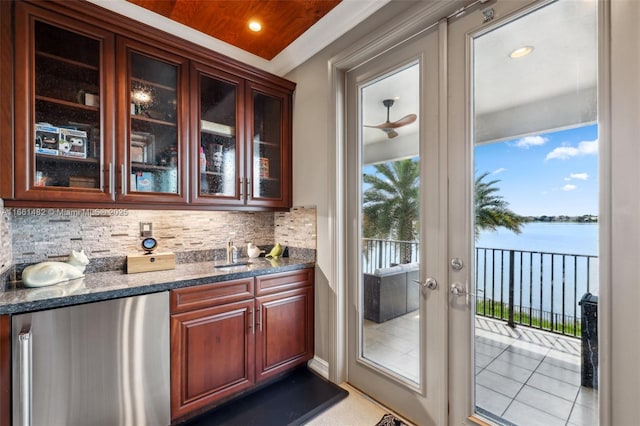 bar featuring plenty of natural light, a water view, decorative backsplash, and stainless steel fridge