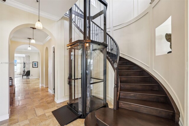 staircase featuring crown molding and a high ceiling