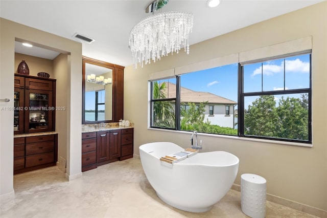 bathroom featuring vanity, an inviting chandelier, and a tub to relax in