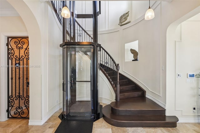 stairway featuring a high ceiling and ornamental molding