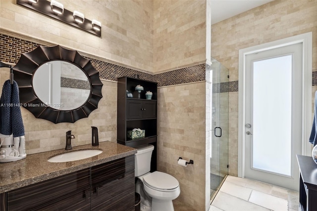 bathroom with toilet, vanity, an enclosed shower, and tile walls