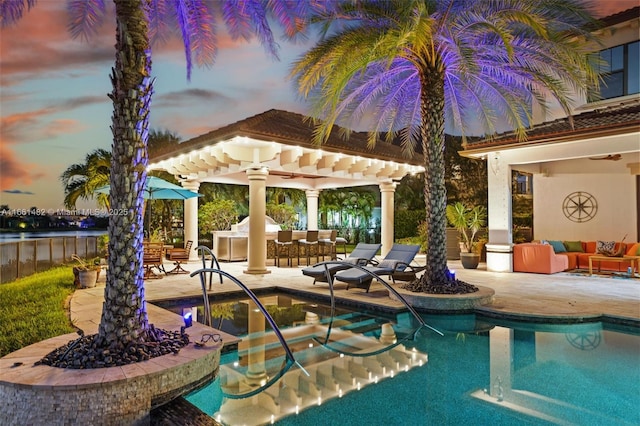 pool at dusk with outdoor lounge area, a patio, a pergola, and a bar