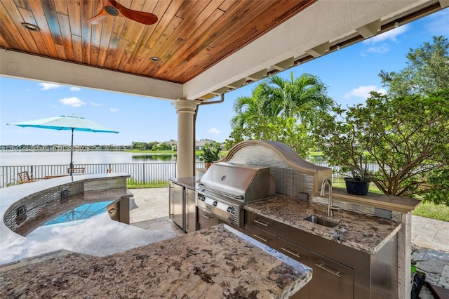 view of patio / terrace with an outdoor kitchen, sink, a water view, a grill, and ceiling fan