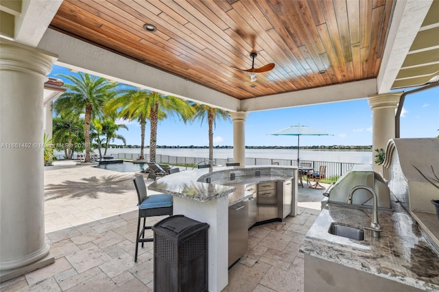 view of patio featuring area for grilling, sink, a water view, and ceiling fan