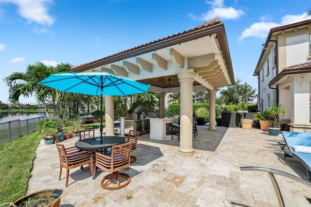 view of patio / terrace featuring a water view, an outdoor kitchen, and grilling area