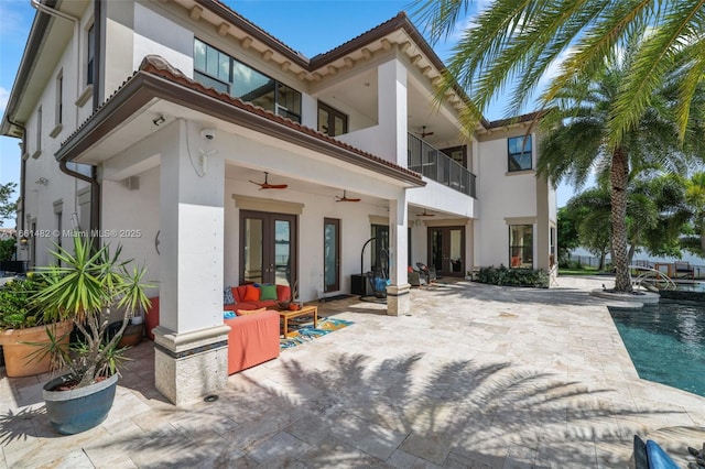 rear view of property with ceiling fan, a fenced in pool, a balcony, and a patio