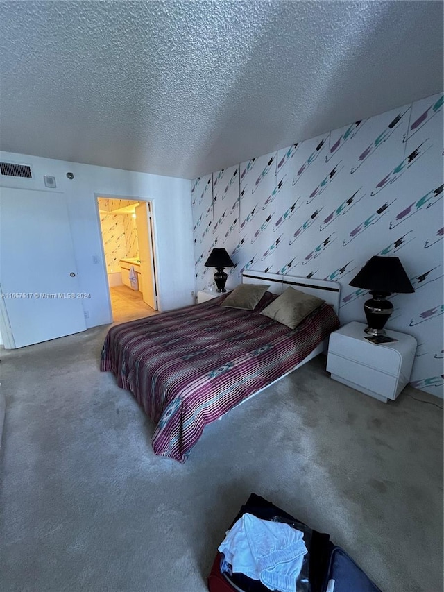 bedroom featuring a textured ceiling, ensuite bathroom, and carpet