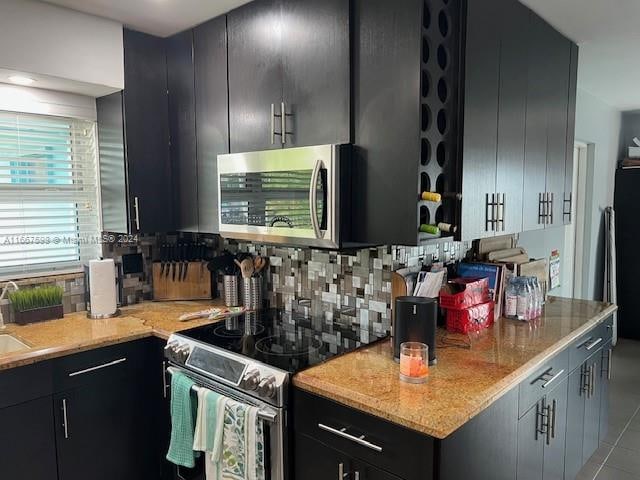 kitchen with light stone countertops, stainless steel appliances, and tasteful backsplash