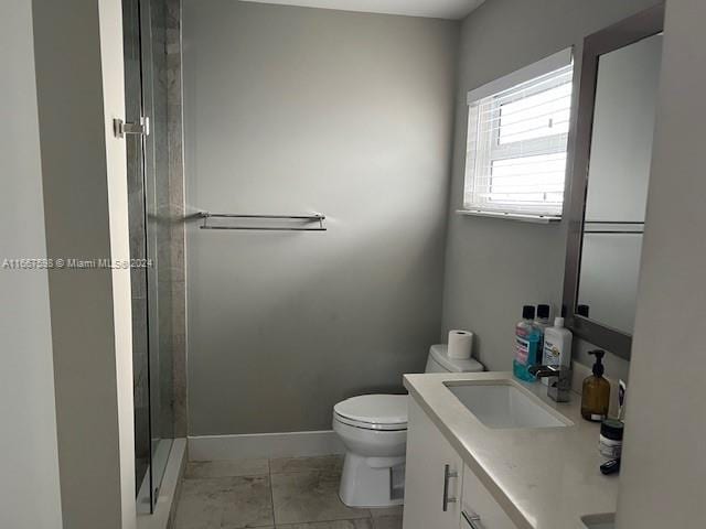 bathroom with tile patterned flooring, vanity, a shower with shower door, and toilet