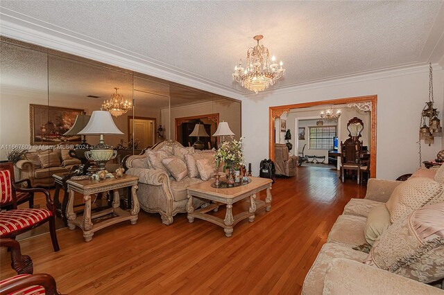 living room with a textured ceiling, crown molding, hardwood / wood-style floors, and a chandelier