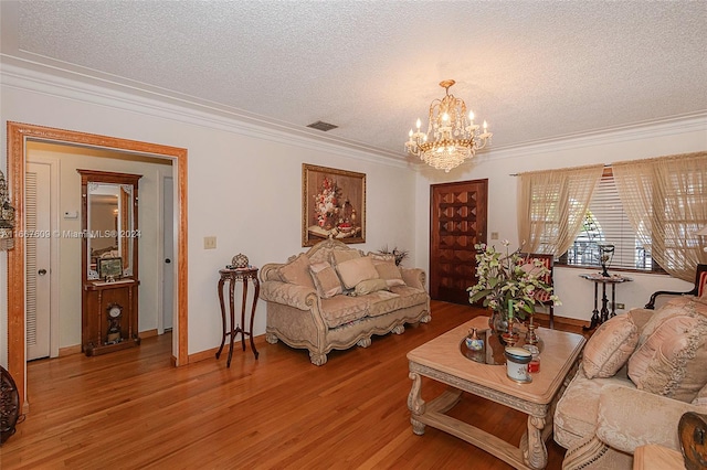 living room featuring a chandelier, a textured ceiling, hardwood / wood-style floors, and crown molding