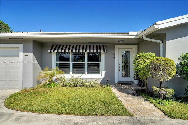 property entrance with a garage and a lawn