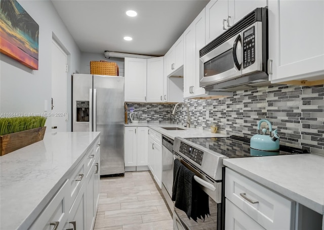 kitchen featuring appliances with stainless steel finishes, backsplash, white cabinetry, and sink