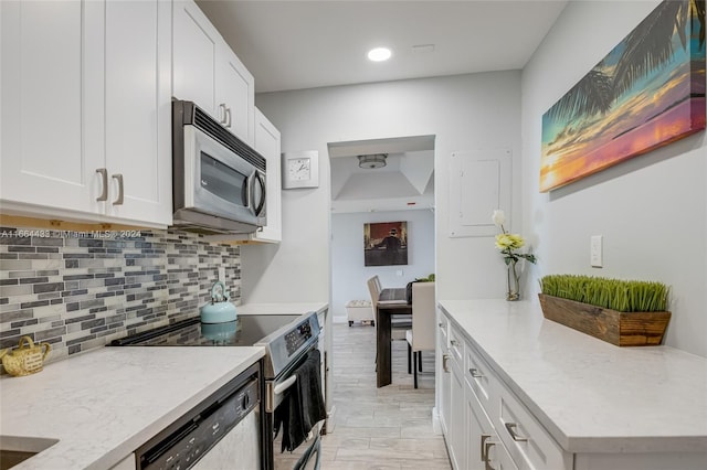 kitchen featuring light stone countertops, backsplash, white cabinetry, appliances with stainless steel finishes, and light wood-type flooring