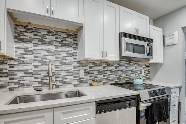 kitchen featuring sink, tasteful backsplash, white cabinetry, appliances with stainless steel finishes, and light stone countertops