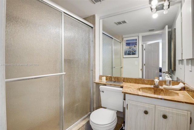 bathroom featuring vanity, toilet, and an enclosed shower