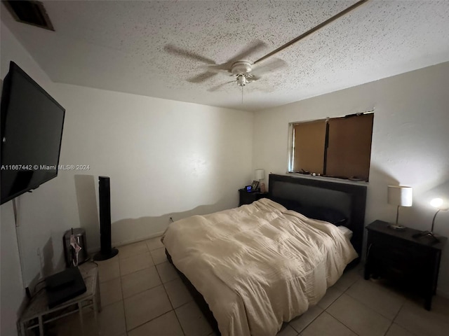 bedroom featuring ceiling fan, light tile patterned floors, and a textured ceiling