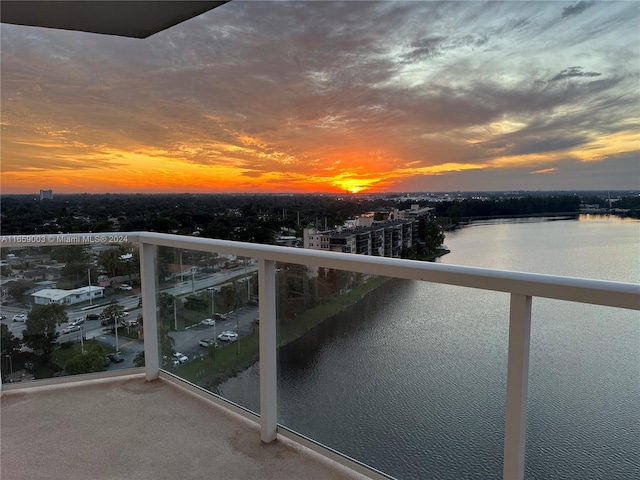 balcony at dusk featuring a water view