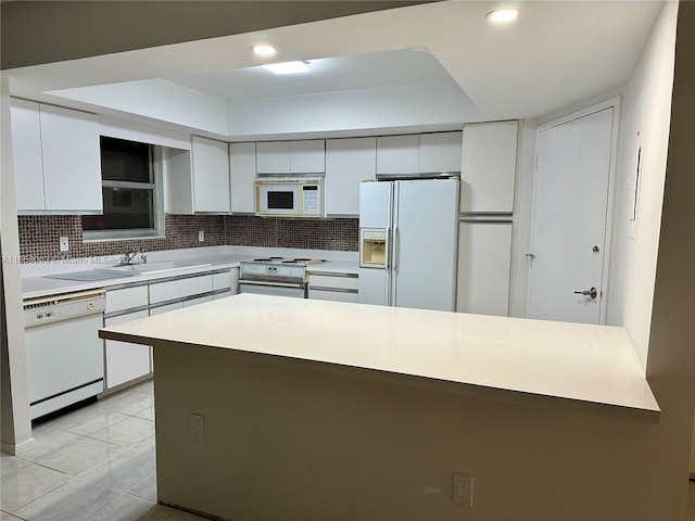 kitchen featuring white appliances, white cabinetry, and backsplash