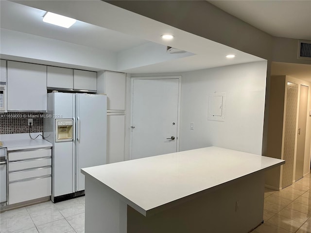 kitchen featuring white fridge with ice dispenser, light tile patterned floors, and a center island