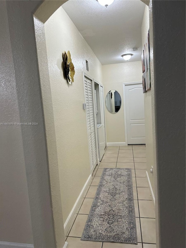 corridor featuring a textured ceiling and light tile patterned flooring