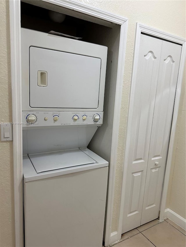 washroom with light tile patterned flooring and stacked washer / dryer