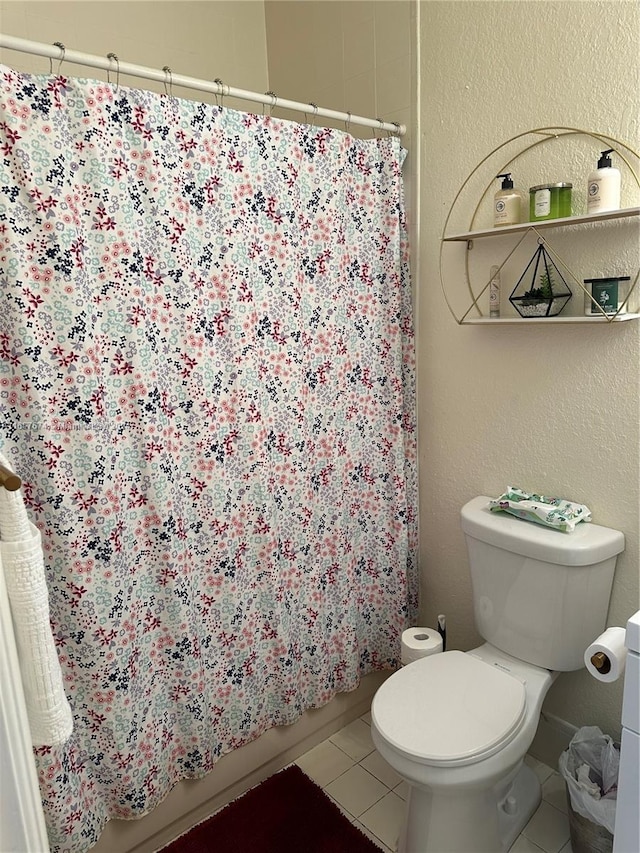 bathroom with a shower with shower curtain, tile patterned floors, and toilet