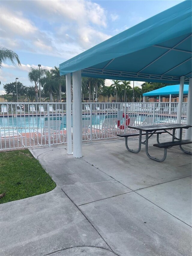 view of home's community with a pool, a water view, and a patio area