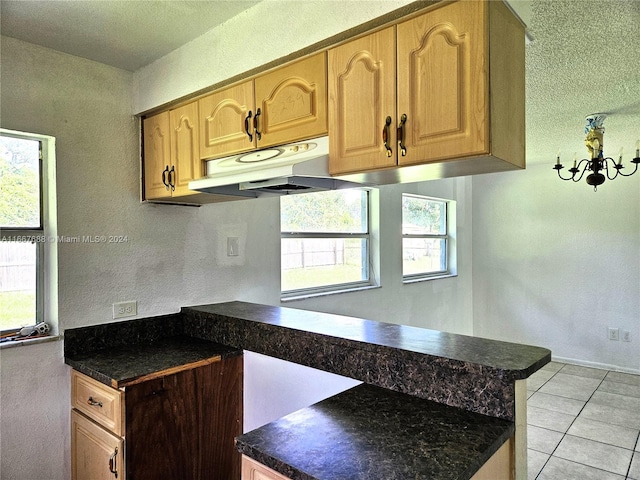 kitchen with a textured ceiling, kitchen peninsula, light tile patterned floors, and a notable chandelier