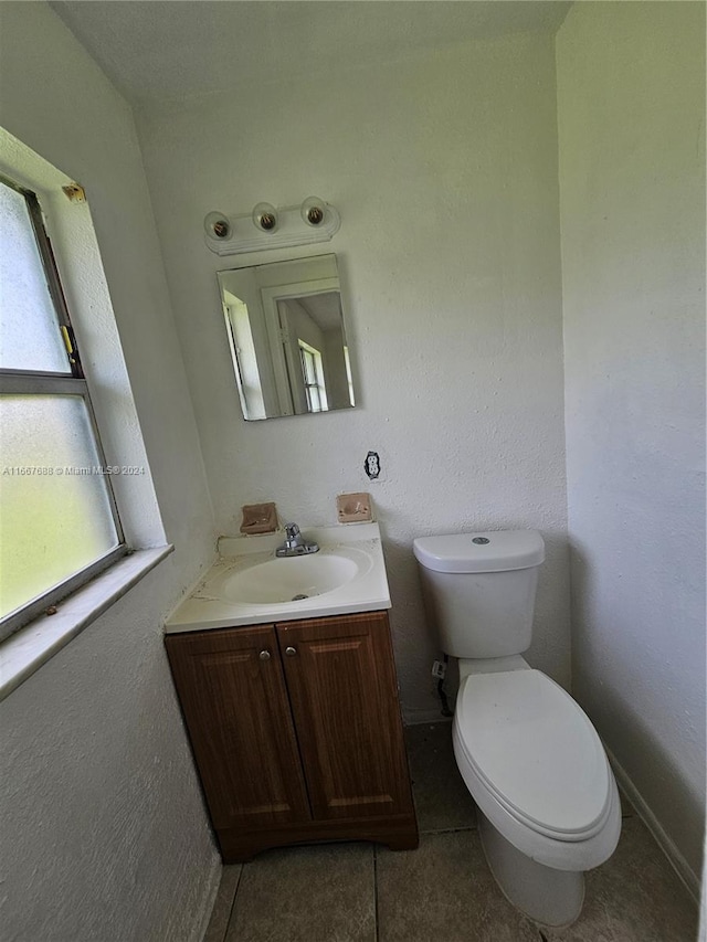 bathroom with vanity, plenty of natural light, toilet, and tile patterned floors