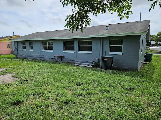 back of property with central air condition unit and a yard