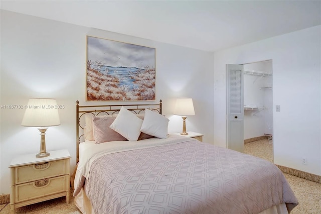 bedroom with light colored carpet and a walk in closet