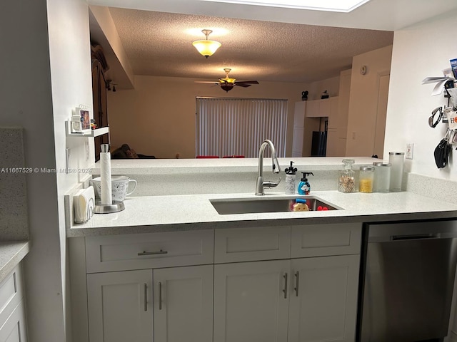 kitchen featuring a textured ceiling, stainless steel dishwasher, sink, and white cabinets