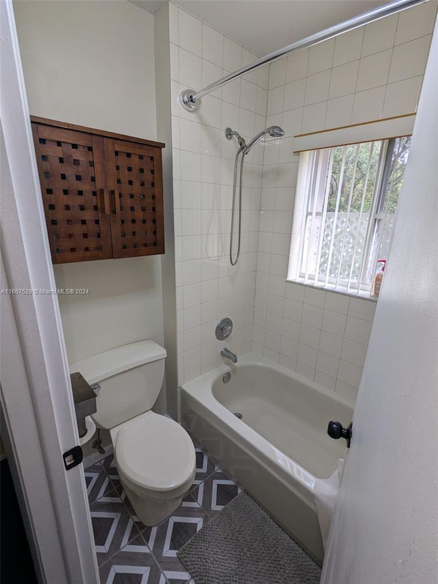 bathroom featuring tiled shower / bath combo, toilet, and tile patterned floors