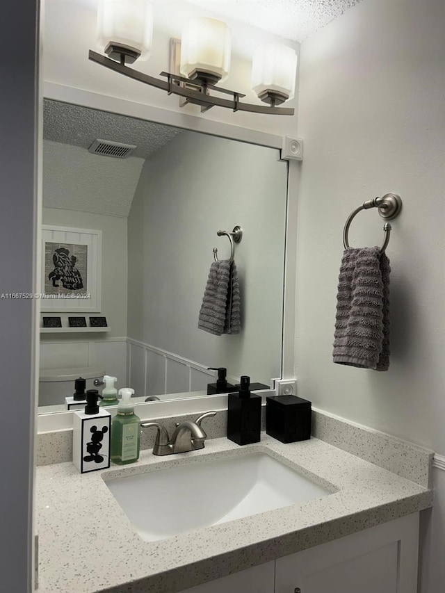 bathroom featuring vanity, vaulted ceiling, and a textured ceiling