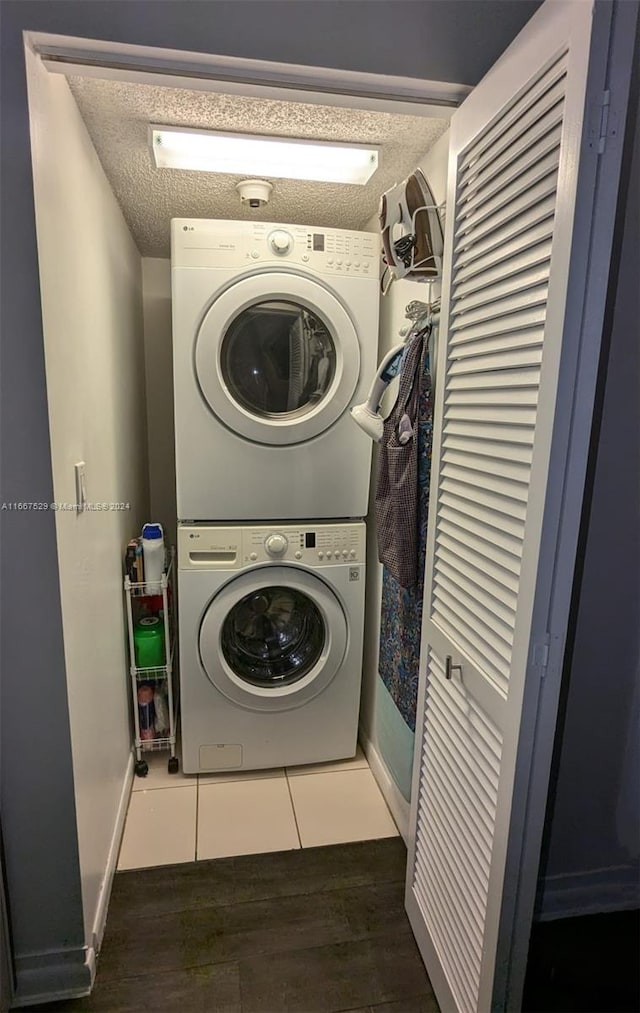 laundry area with a textured ceiling, stacked washing maching and dryer, and dark hardwood / wood-style flooring