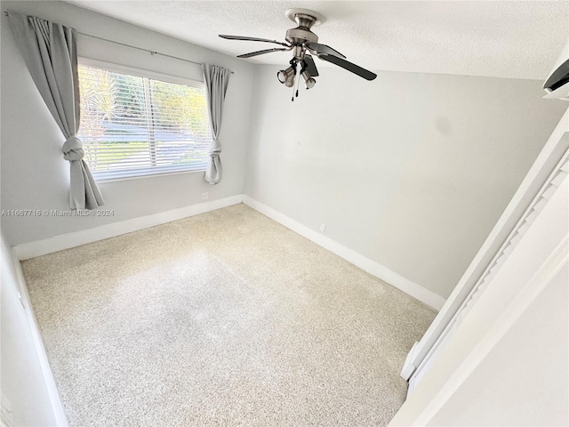 spare room featuring carpet flooring, ceiling fan, and a textured ceiling