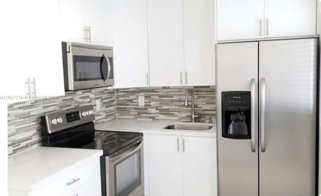 kitchen with tasteful backsplash, sink, white cabinets, and appliances with stainless steel finishes