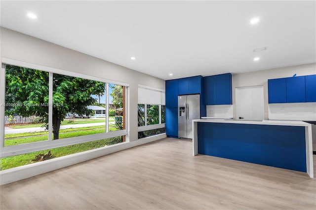 kitchen with light wood-type flooring, blue cabinets, and stainless steel fridge with ice dispenser