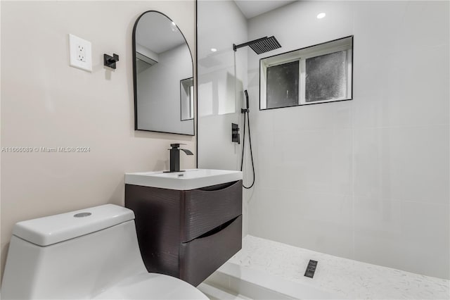 bathroom with vanity, toilet, and tiled shower