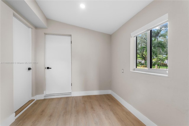 spare room featuring light hardwood / wood-style flooring and vaulted ceiling