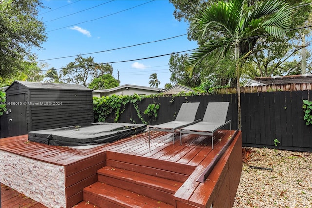 wooden terrace with a covered hot tub and a storage shed