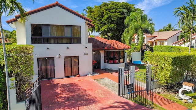 view of front facade featuring a gate, fence, a tiled roof, and stucco siding