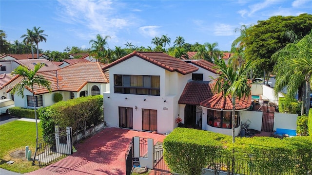 mediterranean / spanish-style house with a tiled roof, fence, a residential view, and stucco siding